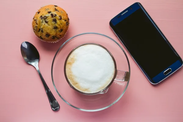 Cup of coffee with cake and a phone on a table