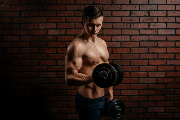 Young sports guy trains biceps