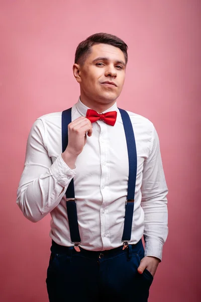 Young stylishly dressed man straightens his bow tie