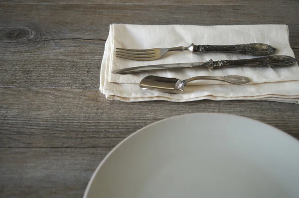 Vintage silverware and dishware on old wooden table, country style in low natural light