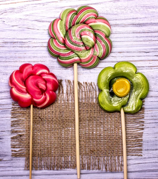 Lollipop candy flowers on a grey wooden and sack background