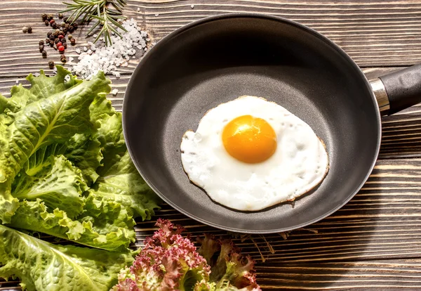 Fried sunny side up eggs on a pan on a brown oak old wooden board