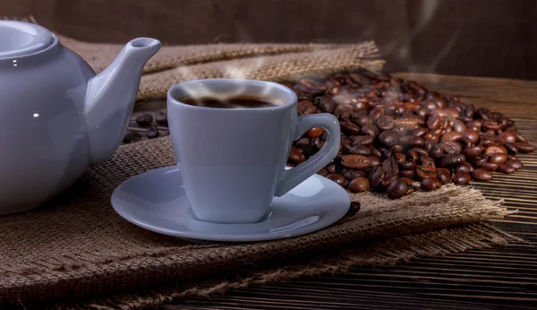 Coffee cup and coffee beans with  smoke on table