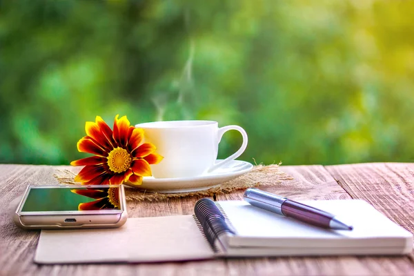 Blank white notebook, flowers and cup of coffee on the desk