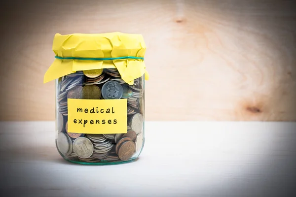 Financial concept. Coins in glass money jar with medical expenses label