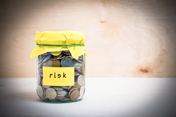 Financial concept. Coins in glass money jar with risk label