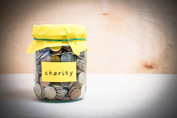 Financial concept. Coins in glass money jar with charity label