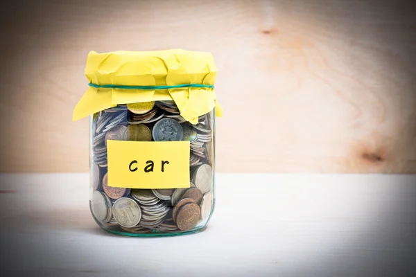 Financial concept. Coins in glass money jar with car label