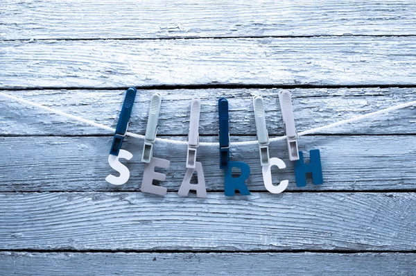 Word search fasten clothespins on a rope behind a wooden background