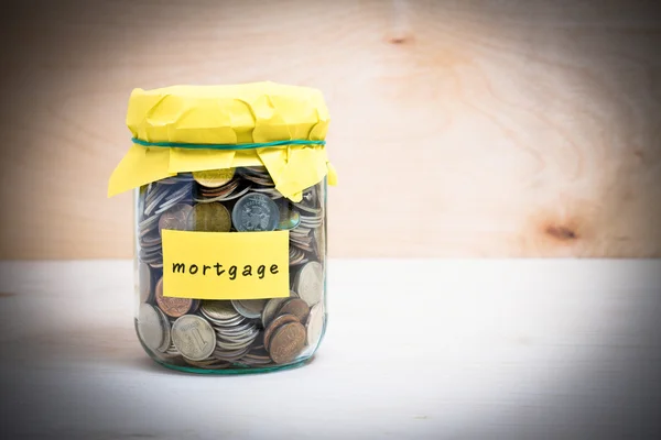 Coins in glass money jar with mortgage label.