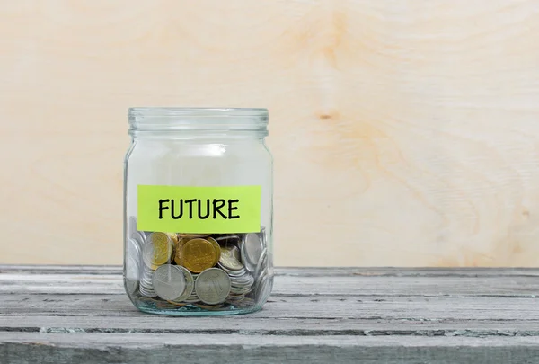 Label on a glass jar with the inscription - future. Glass jar with coins. Financial concept on wooden background