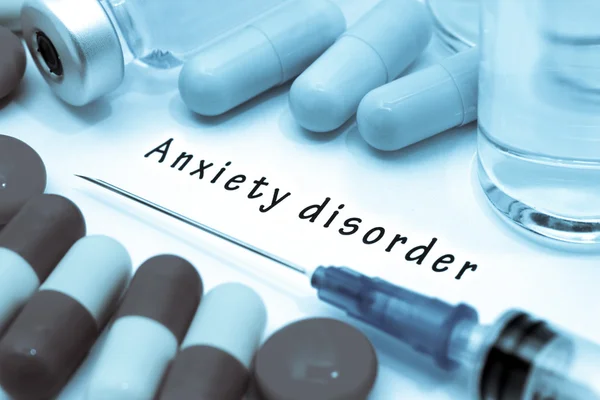 Anxiety disorder - diagnosis written on a white piece of paper. Syringe and vaccine with drugs.