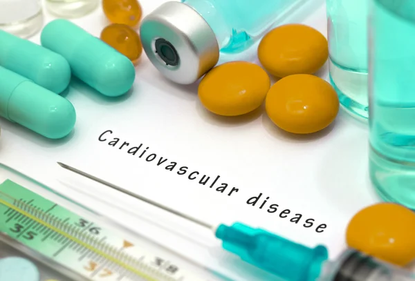 Cardiovascular disease - diagnosis written on a white piece of paper. Syringe and vaccine with drugs.