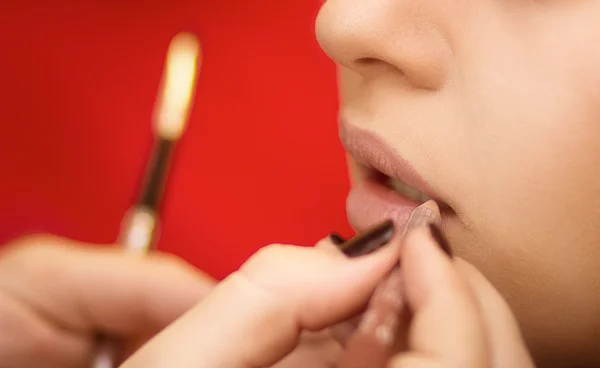 Make-up artist applying lip liner on model\'s lips, close-up, selective focus on model