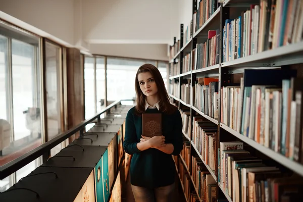 Beautiful girl in the library, smart. Fourteen years old. Education, school, college, exams. Preparation for school.