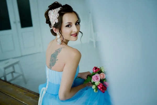 Beautiful girl in a wedding dress, the bride with a bouquet. The blue dress. In the soft light, in a beautiful interior. In the photo studio.