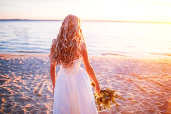 Bride in wedding dress at the beach  sunset