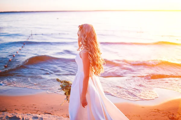 Bride in wedding dress at the beach sunset