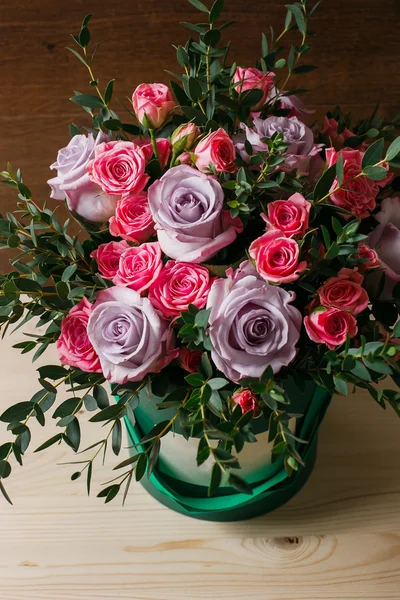 Rich bunch of pink eustoma and roses flowers, green leaf in hand Fresh spring bouquet. Summer Background. composition hatbox