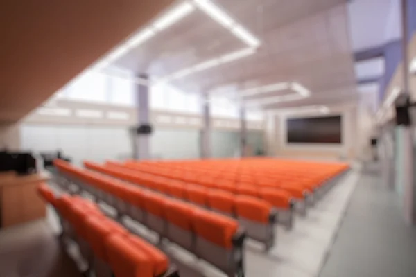 Abstract blur Rostrum with microphone and computer in conference hall. Orange color