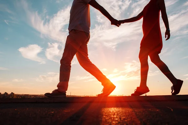 Silhouettes of happy couple running down at sunset, perfect love background.