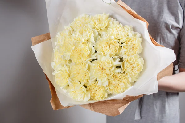 Soft yellow carnations flower in the hands of the florist. kraft paper