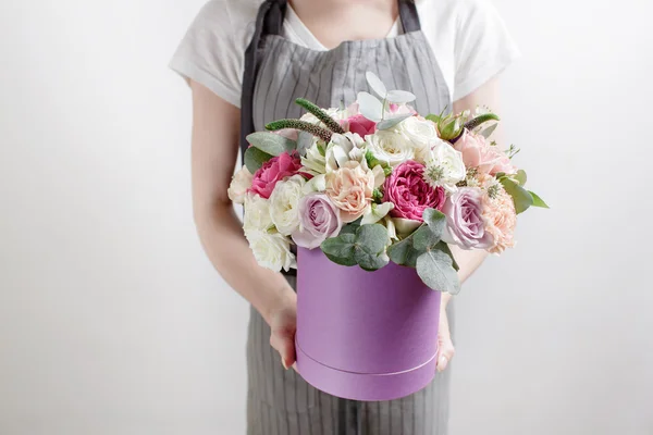 Florist collects bouquet. holding a bunch of hands,  box in the foreground. Pink and white roses