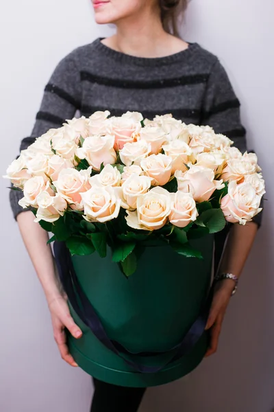 Luxury bouquets of flowers in the hat box. roses in the hands women. Peach Colour