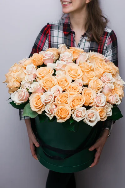 Luxury bouquets of flowers in the hat box. roses in the hands  women. Peach Colour