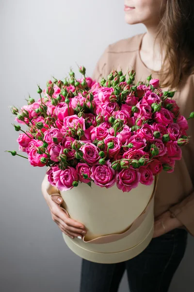 Luxury bouquets of flowers in the hat box. roses in the hands women. Pink Colour peonies