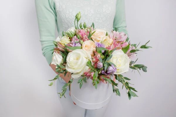 Mixed bouquet of various flowers in a hat box in womans hands