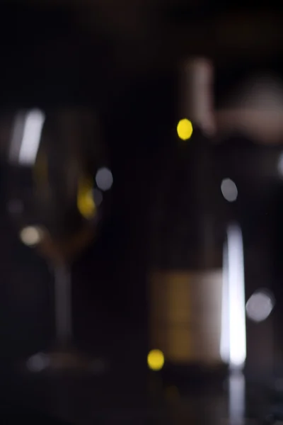 Out of focus Bottle white wine with glass against a dark background