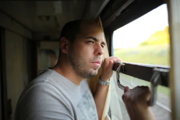 Handsome man looking out the open train window outside