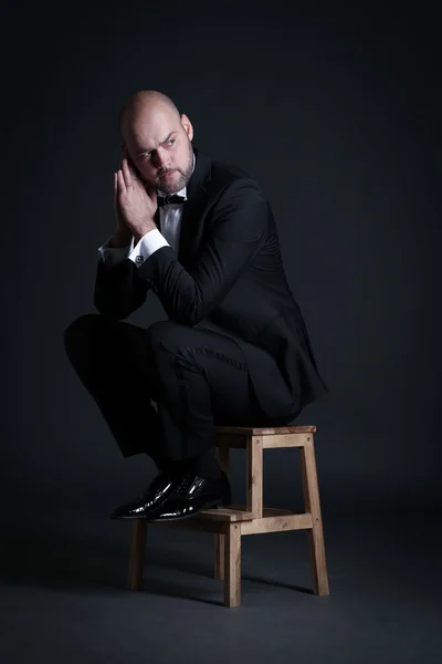 Stylish and brutal bald man with a beard sitting