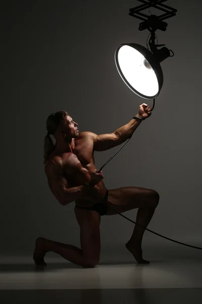 Young naked man, sexy strong muscular body with studio lighting