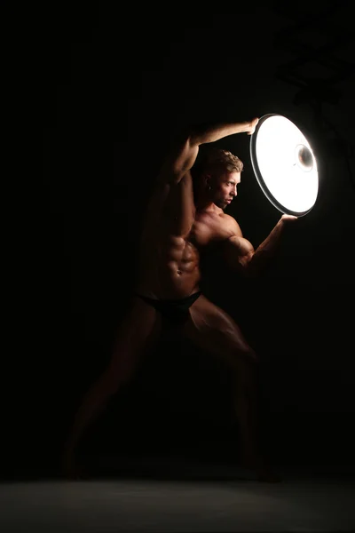 Young naked man, sexy strong muscular body with studio lighting