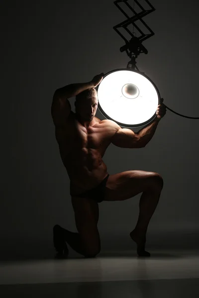 Young naked man, sexy strong muscular body with studio lighting