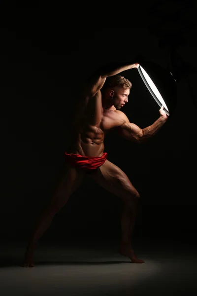 Young naked man, sexy strong muscular body with studio lighting
