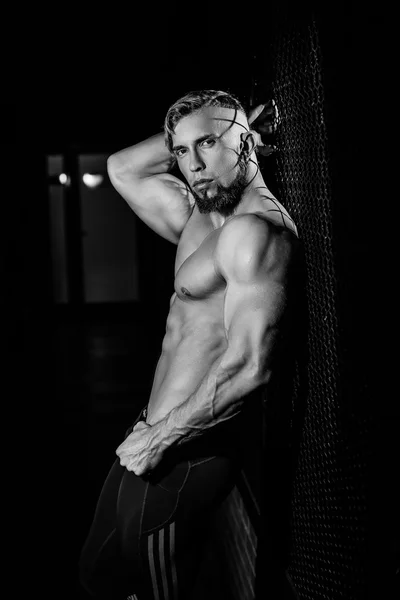 Young muscular man near fence grid. Black and white photo