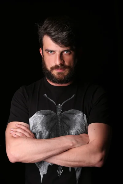 Bearded guy posing with crossed hands. Close.up. Black