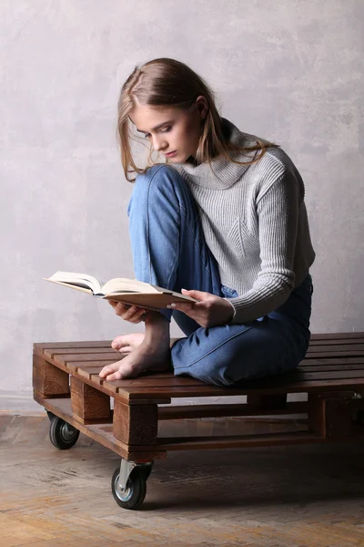 Sitting girl reading a book. Gray background