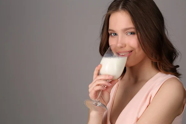 Lady drinking milk from a bocal. Close up. Gray background