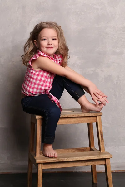Portrait of a girl with makeup posing on chair. Gray background