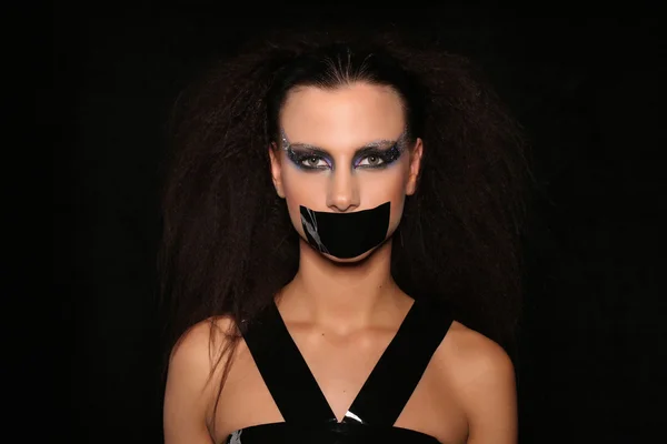 Girl with adhesive tape on her mouth. Close up. Black background