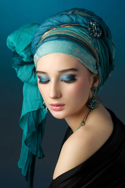 Romantic portrait of young woman in a turquoise turban on a beau