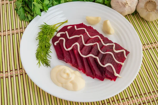 Slices of boiled beets on a white plate with mayonnaise
