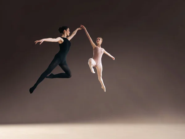 Two ballet dancers jumping high, in air.