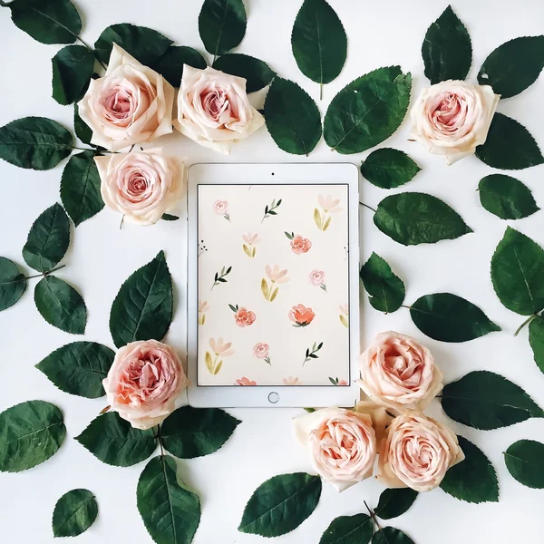 Tablet and pink rose flowers