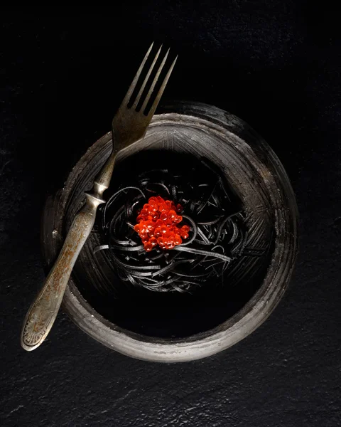 Black pasta with red caviar