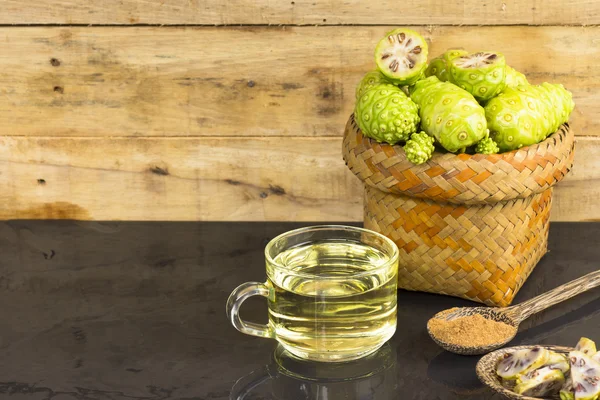 Noni fruit and noni juice with noni powder on black table.Fruit for health and herb for health